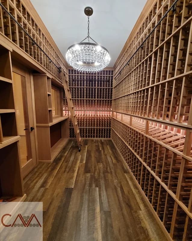 Tall wood wine racks line a narrow cellar beneath a pendant light.