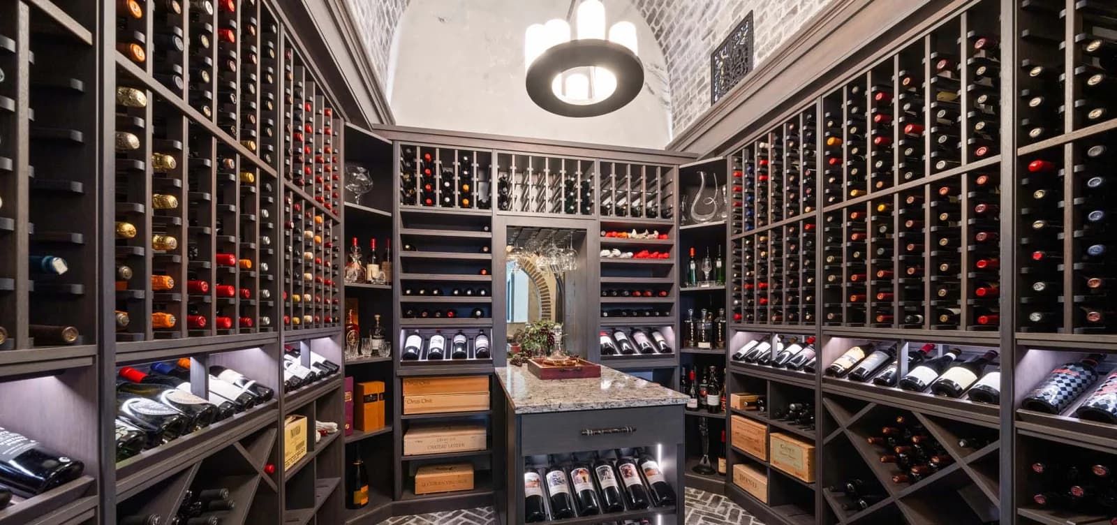 A wine cellar with dark wood racks, a central island, and a decorative ceiling light.