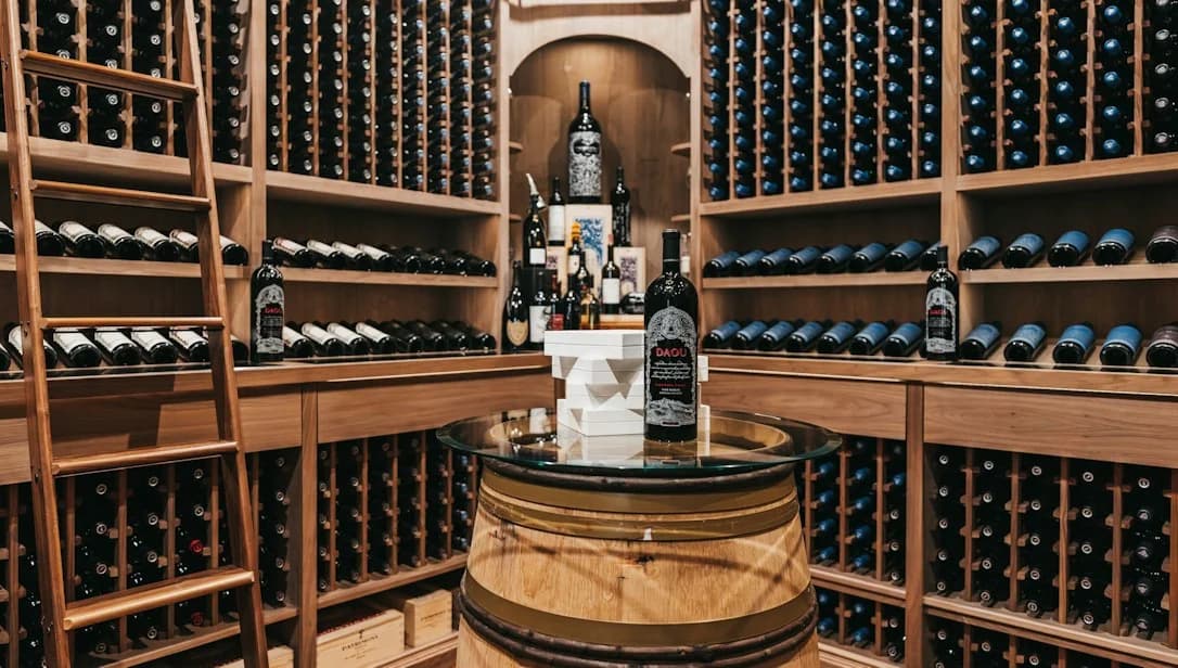 Wood wine racking surrounds a barrel tasting table in a traditional cellar.