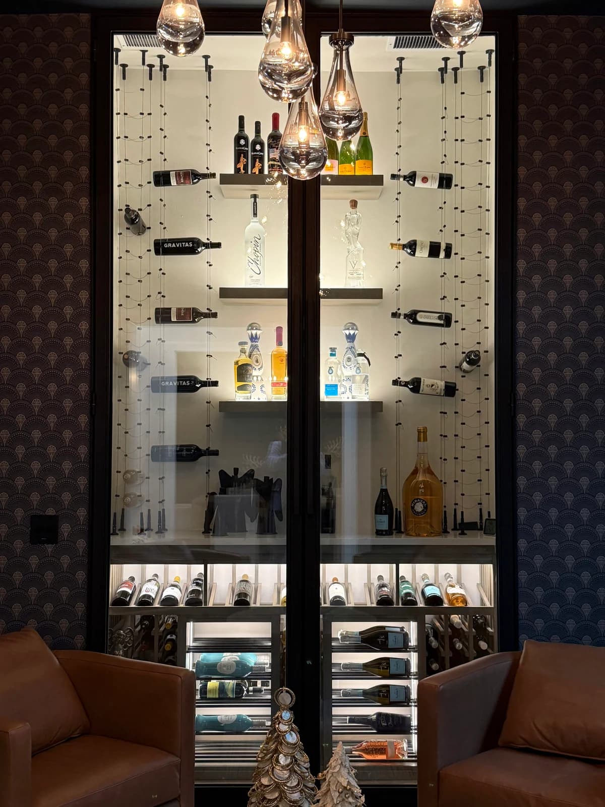 A completed glass-front wine display with metal bottle racks and patterned backing.